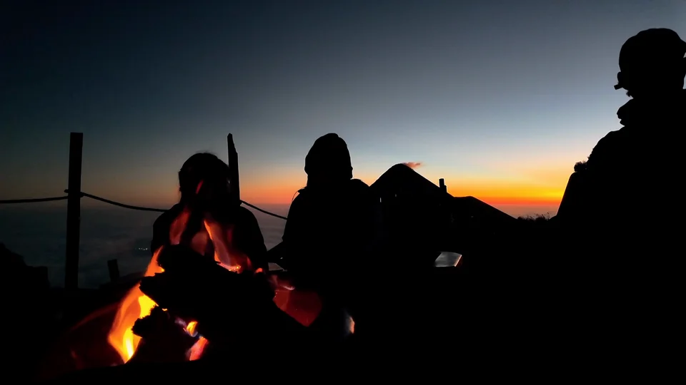 Silhouetted hikers watching sunset from Acatenango volcano campsite, Guatemala