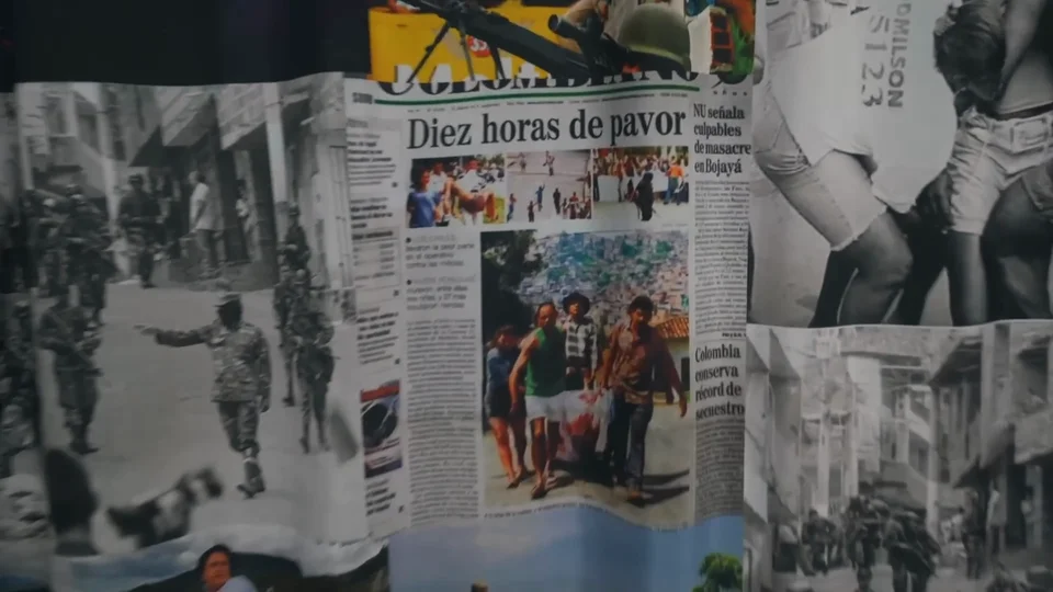 Wall of old newspaper front pages documenting Medellín's cartel era history in Comuna 13