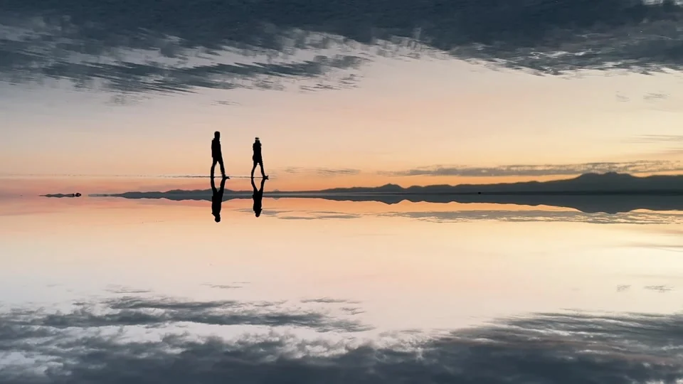 Walking onto the mirror-like Uyuni Salt Flats at sunset