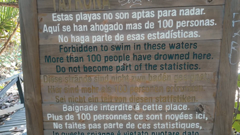 Multilingual warning sign about dangerous currents in Tayrona National Park