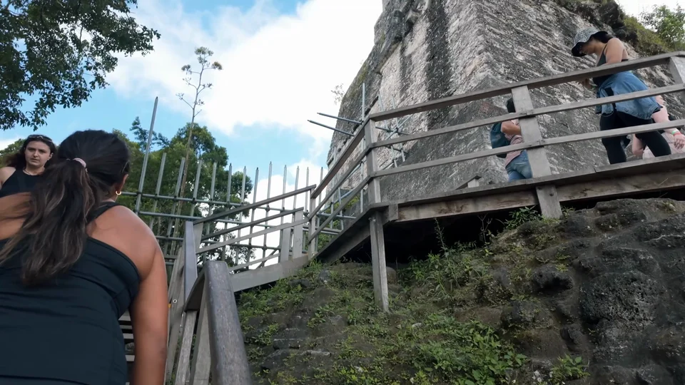 Climbing the wooden staircase up Temple IV at Tikal, Guatemala