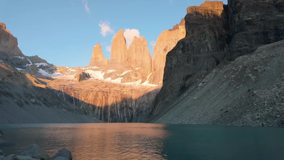 Sunrise light hitting the granite towers of Torres del Paine, reflected in the lake below