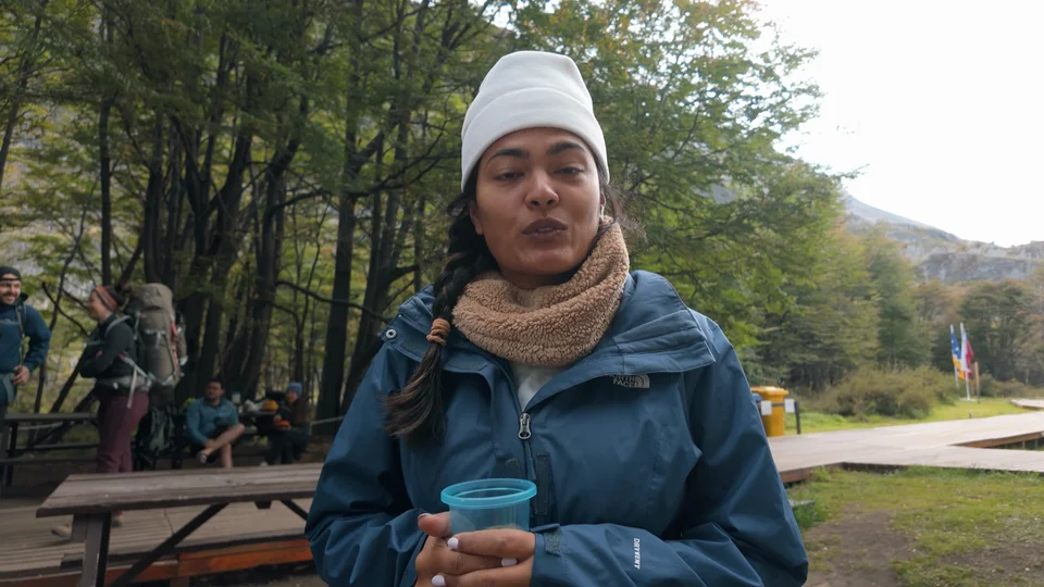 Hiker relaxing with a drink at the campsite on the final night of the W Trek