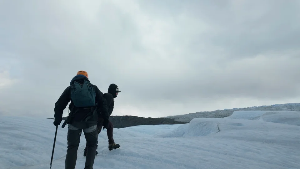 Hikers walking across the Grey Glacier roped up with crampons and ice axes