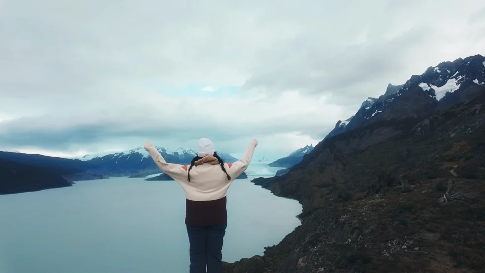 Hiker with arms raised overlooking Lago Grey towards the Grey Glacier, Patagonia